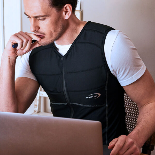 Uomo indossa una maglia smanicata refrigerante E.COOLINE di colore nero e lavora al suo computer portatile.
