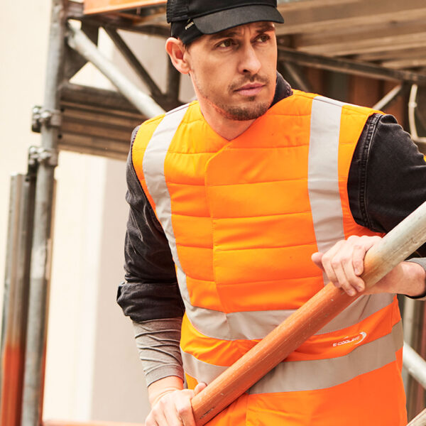 Operaio edile che indossa il gilet refrigerante SX3 con inserti riflettenti di E.COOLINE nel colore arancione segnaletico.