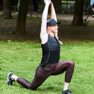 Donna con maglietta rinfrescante di E.COOLINE mentre fa stretching all'aperto